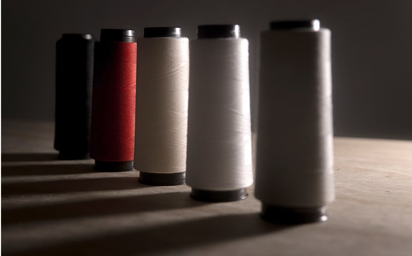 Thread spools arranged in window light — placeholder editorial cover.
